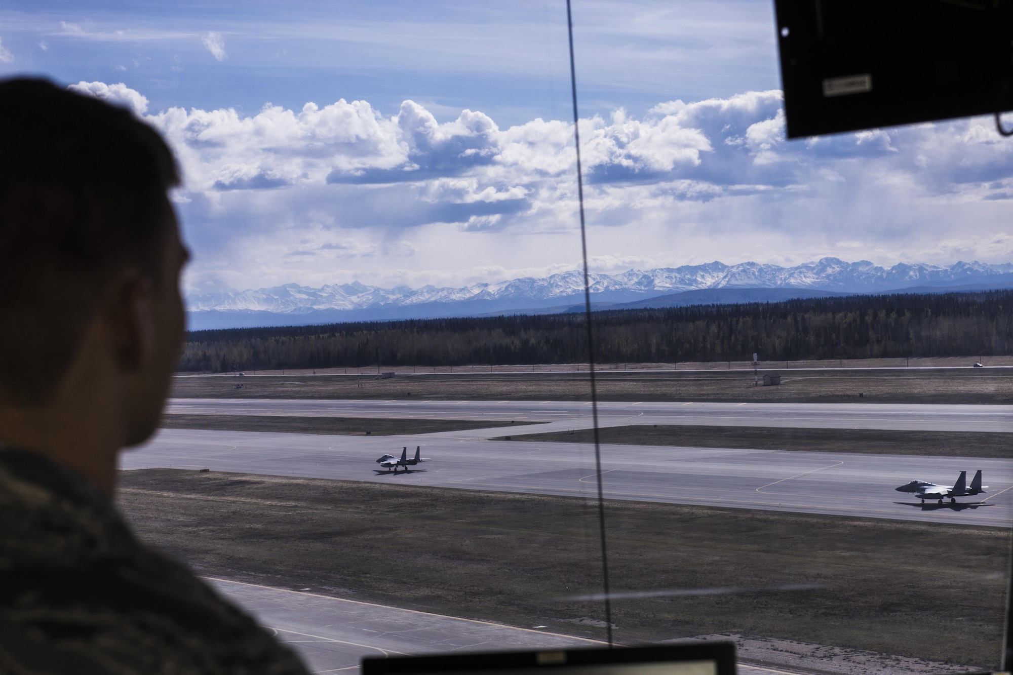 U.S. Air Force Senior Airman Eric Smith, a 354th Operations Support Squadron air traffic controller, watches two F-15 Eagle tactical fither jets assigned to the 67th Fighter Squadron, Kadena Air Base, Japan, May 5, 2016, during RED FLAG-Alaska (RF-A) 16-1. RF-A usually brings various airframes into the mission which, adds complexity to the air traffic controllers’ mission. (U.S. Air Force photo by Staff Sgt. Joshua Turner/Released)