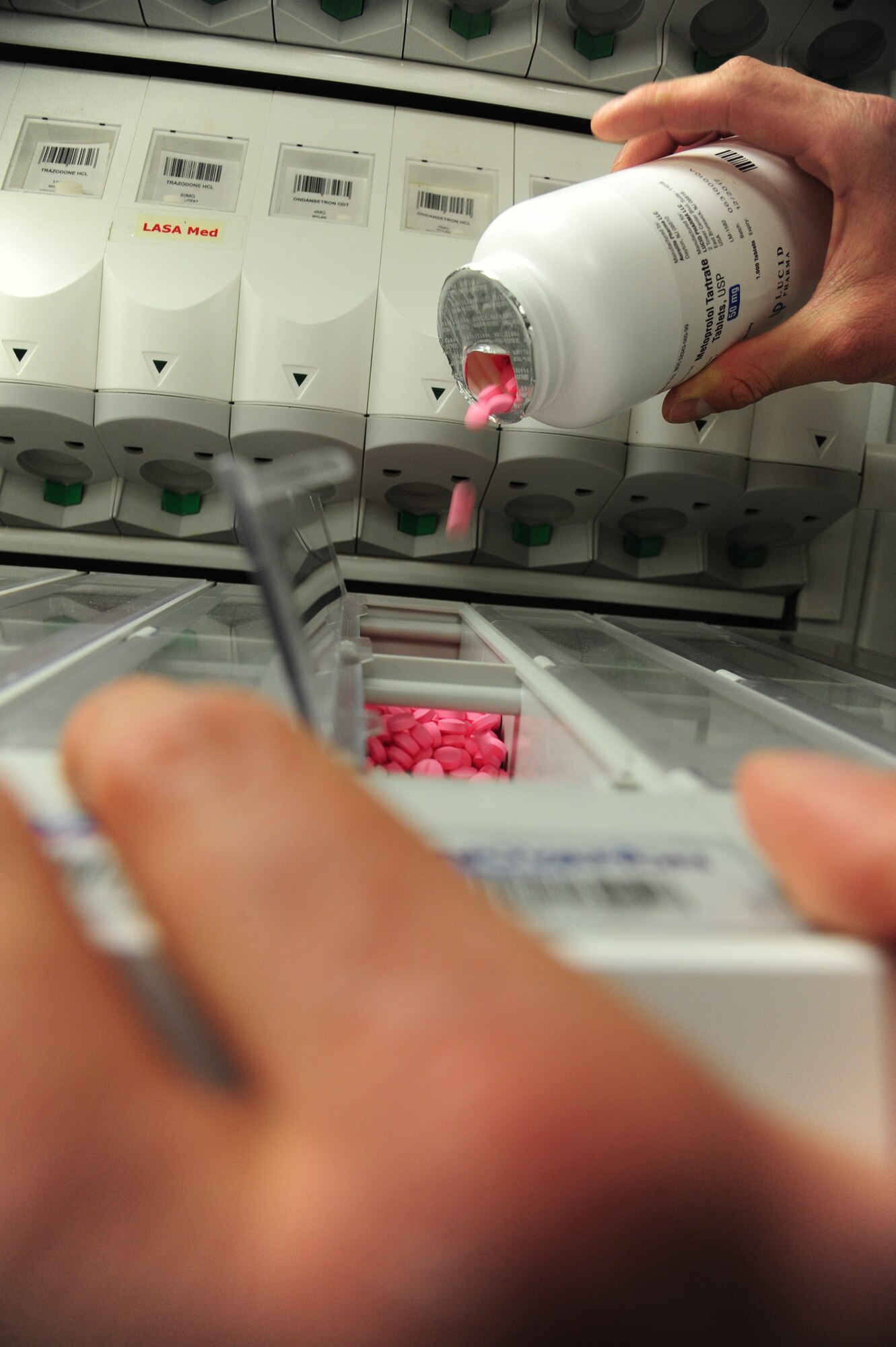 U.S. Air Force Senior Airman Marco Cardenas, a 509th Medical Support Squadron pharmacy technician, replenishes an automated counting machine at Whiteman Air Force Base, Mo., April 20, 2016. The automated counting machine is designed to ensure an accurate amount of medication is distributed for each prescription before being issued to the patient.  (U.S. Air Force photo by Airman 1st Class Keenan Berry) 