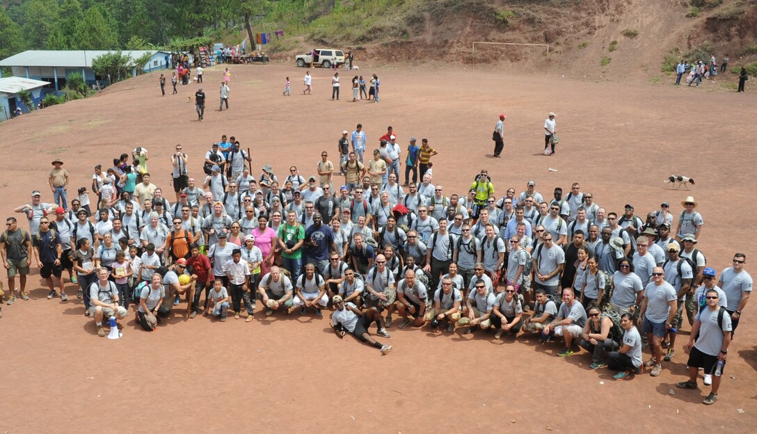 Volunteers from Joint Task Force-Bravo pose for a group photo after distributing 150 bags of food weighing 20 pounds apiece to the 172 families of Montaña La Oki, a small village located in the mountains east of Comayagua, Honduras, during Chapel Hike 67, April 30, 2016. During the visit to Montaña La Oki, U.S. service members had the opportunity to watch local school children perform cultural dances, play soccer and hand out the bags of food to villagers as well as some Hondurans who traveled to the location on horseback from the surrounding mountains. (U.S. Air Force photo by Capt. David Liapis/Released)
