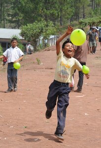 A Honduran boy from the village of Montaña La Oki, located in the mountains east of Comayagua, Honduras, plays with a balloon given to him by one of the 158 military and civilian members of Joint Task Force-Bravo and volunteer firefighters from the local area who hiked 7.4 miles roundtrip to deliver 3,000 pounds of food to 172 families in the village April 30, 2016. During the visit to Montaña La Oki, U.S. service members had the opportunity to watch local school children perform cultural dances, play soccer and hand out the bags of food to villagers as well as some Hondurans who traveled to the location on horseback from the surrounding mountains. (U.S. Air Force photo by Capt. David Liapis/Released)