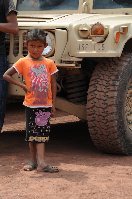 A Honduran girl from the village of Montaña La Oki, located 4,406 feet above sea level in the mountains east of Comayagua, Honduras, rests from playing in front of a Joint Task Force-Bravo, Joint Security Forces Humvee that served as a pilot vehicle for 158 military and civilian members of Joint Task Force-Bravo and volunteer firefighters from the local area who hiked 7.4 miles roundtrip to deliver 3,000 pounds of food to 172 families in the village April 30, 2016. In addition to the ton-and-a-half of food, which was packed into 150 bags containing 20 pounds apiece by volunteers two nights prior to the trek, many hikers brought their own additional treats and toys to give to the dozens of children they met at the top of the mountain. (U.S. Air Force photo by Capt. David Liapis/Released)