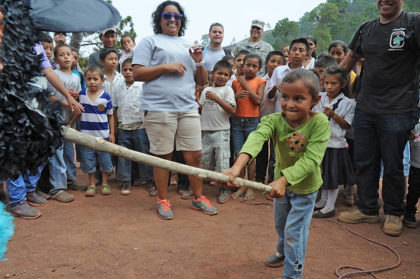A Honduran girl from the village of Montaña La Oki, located 4,406 feet above sea level in the mountains east of Comayagua, Honduras, attempts to break open a piñata given to the village children during Chapel Hike 67, April 30, 2016. More than 158 military and civilian members of Joint Task Force-Bravo and volunteer firefighters from the local area hiked 7.4 miles roundtrip to deliver 3,000 pounds of food to 172 families. In addition to the ton-and-a-half of food, which was packed into 150 bags containing 20 pounds apiece by volunteers two nights prior to the trek, many hikers brought their own additional treats and toys to give to the dozens of children they met at the top of the mountain. (U.S. Air Force photo by Capt. David Liapis/Released)