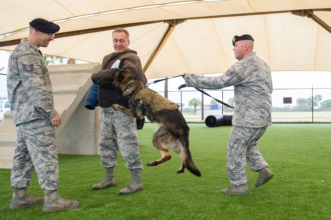 Tech. Sgt. Brandon Serena, Military Working Dog kennel master, left, and Staff Sgt. Robert Ford, MWD trainer, right, perform a MWD demonstration for Lt. Gen. David J. Buck, commander, 14th Air Force (Air Forces Strategic), Air Force Space Command; and commander, Joint Functional Component Command for Space, U.S. Strategic Command, May 4, 2016, at Patrick Air Force Base, Florida. Buck and Chief Master Sgt. Craig Neri, 14th AF command chief and command senior enlisted leader for JFCC Space, visited Patrick Air Force Base and Cape Canaveral Air Force Station May 4 and 5 and gained insight into the contributions Airmen across the wing make to keep the 45th Space Wing the World's Premier Gateway to Space. (U.S. Air Force photo by Matthew Jurgens/Released)