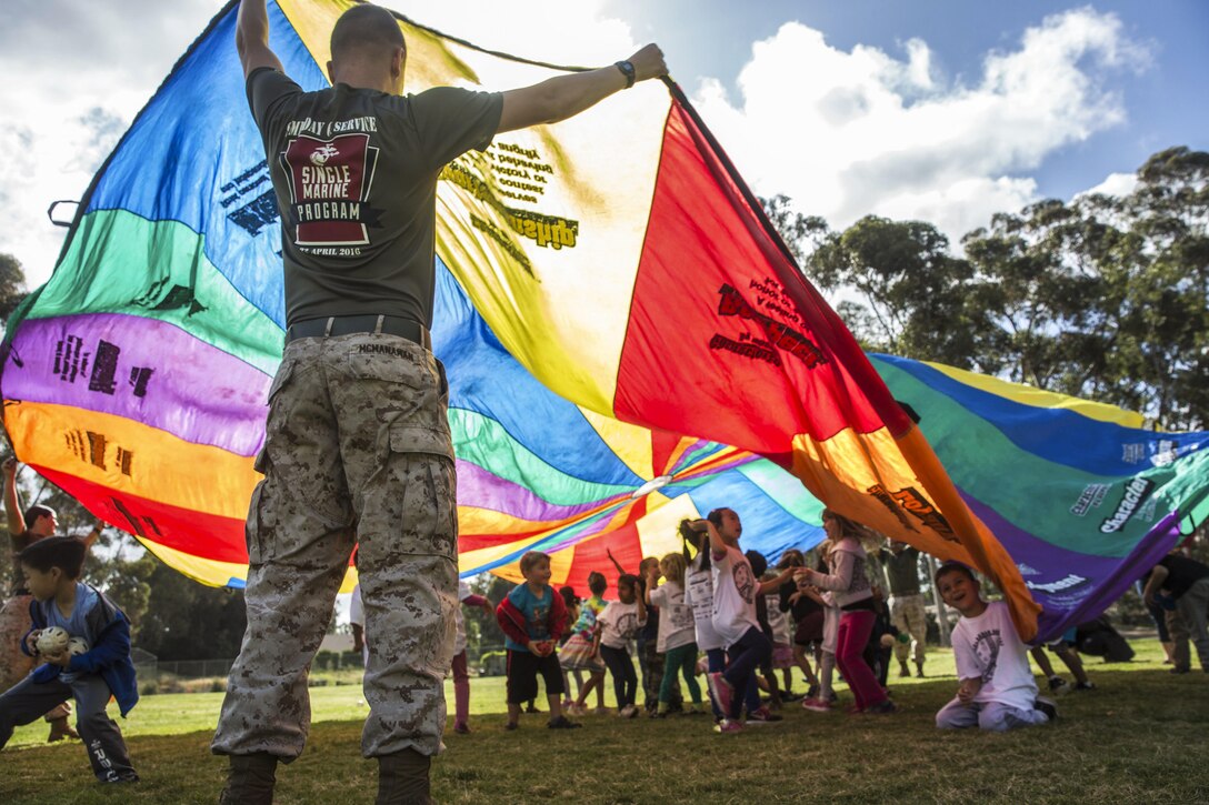Marine Corps Lance Cpl. Chase McManaman holds a parachute during an activity at an elementary school in San Diego, April 29, 2016. Marines volunteered for a fitness challenge, which allowed children and Marines to complete a series of exercise stations during the school day. McManaman is a volunteer with the Single Marine Program at Marine Corps Air Station Miramar. Marine Corps photo by Sgt. Lillian Stephens