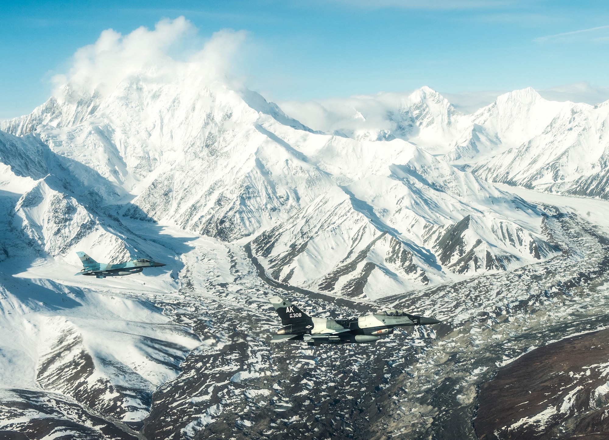U.S. Air Force Major’s Clinton Garrett (left) and Jeromy Guinther (right), 18th Aggressor Squadron pilots, fly an F-16 Fighting Falcon aircraft on May 4, 2016, over the Joint Pacific Alaska Range Complex during RED FLAG-Alaska (RF-A) 16-1. RF-A is a Pacific Air Forces command directed field training exercise for U.S. and allied forces, to provide joint offensive counter-air, interdiction, close air support and large force employment training in a simulated combat environment. (U.S. Air Force photo by Staff Sgt. Shawn Nickel/Released)