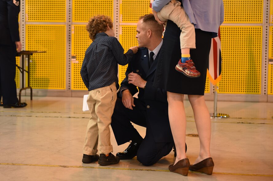 Lt. Col. Gibb Little, commander 423rd Civil Engineer Squadron, kneels to let his wife and children pin on his new rank at his promotion ceremony, April 1, 2016, at RAF Alconbury. Little spoke on the importance of his family during his promotion ceremony. 