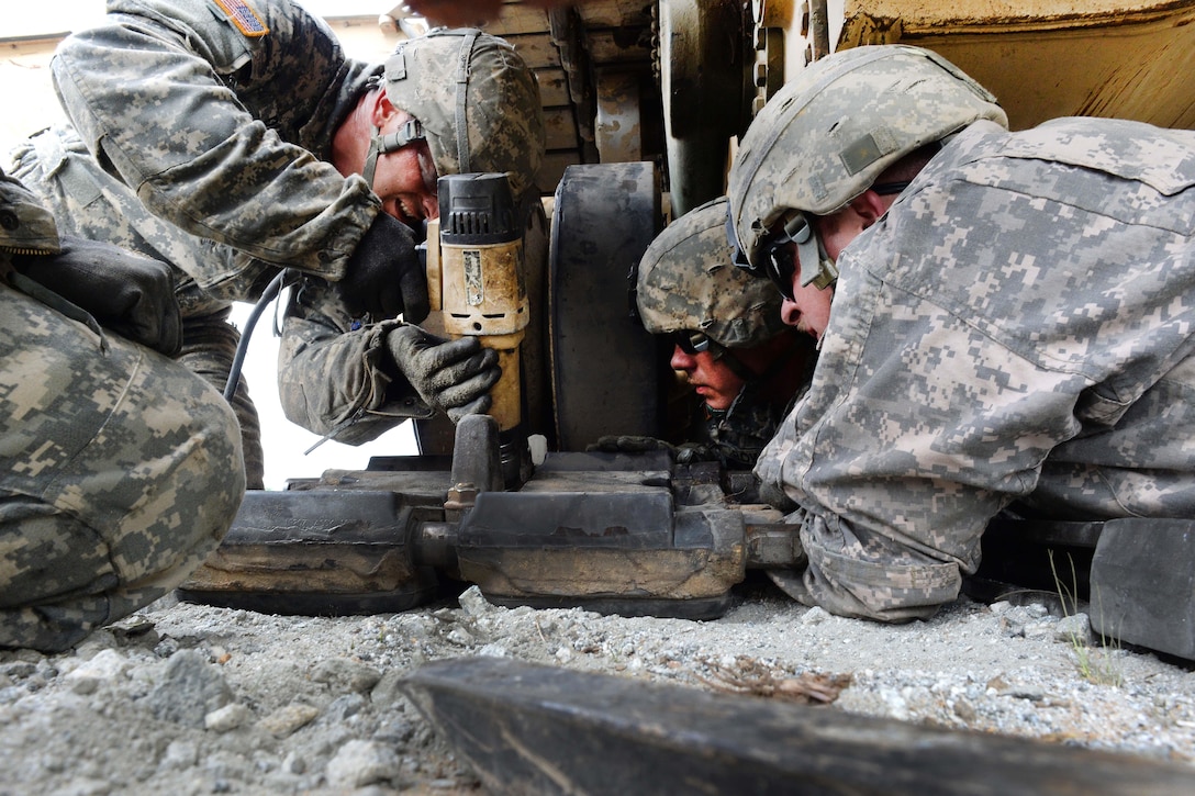 Army 1st Lt. John Dupre, left, uses an impact wrench to tighten bolts on a section of track on an M1A2 Abrams tank as Sgt. Curtis Bowen, center, and Spc. Brandon Sinor support the track and make adjustments to its positioning during the Gen. Gordon Sullivan Cup best tank crew competition at Fort Benning, Ga., May 2, 2016. Dupre, Bowen and Sinor are assigned to the North Carolina Army National Guard’s Company C, 1st Battalion, 252nd Armor Regiment. Army photo by Sgt. 1st Class Jon Soucy