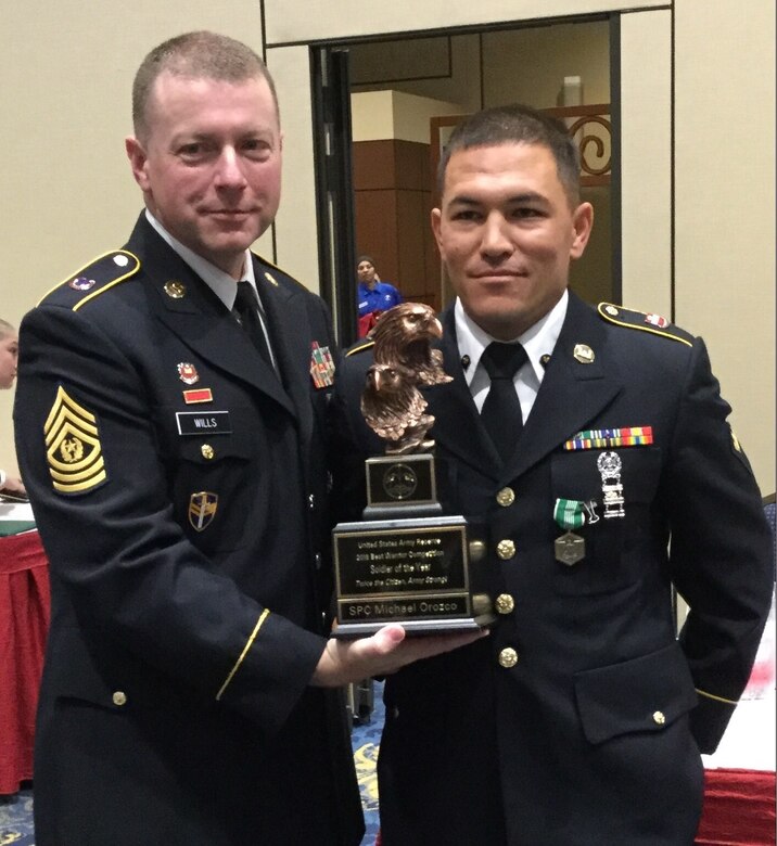 Spc. Michael S. Orozco, right, representing the 416th Theater Engineer Command, accepts the Soldier of the Year trophy from Command Sgt. Maj. James P. Wills, interim command sergeant major of the U.S. Army Reserve, at the U.S. Army Reserve Best Warrior Competition awards luncheon, May 6, at the Iron Mike Conference Center, Fort Bragg, N.C. Orozco will represent the U.S. Army Reserve at the Army Best Warrior Competition later this year at Fort A.P. Hill, Va. (U.S. Army photo by Timothy L. Hale) (Released)