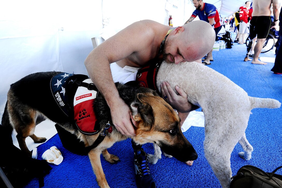 Retired Navy Seaman Brett Parks hugs military working dogs belonging to U.S. swim team members after competing in his preliminary swim event at the 2016 Invictus Games in Orlando, Fla., May 7, 2016. Air Force photo by Staff Sgt. Carlin Leslie