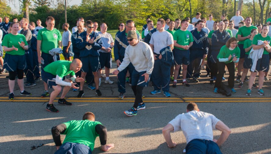 Col. Andres Nazario, Global Exploitation Intelligence Group commander, cheers on his Airmen during a "Burpee Challenge" after the first National Air and Space Intelligence Center run of the season, May 6, 2016. The center staff participates in runs during the spring and summer  in an effort to foster positive teamwork amongst members and boost morale. (U.S. Air Force photo/Tech. Sgt. Eunique P. Thomas)