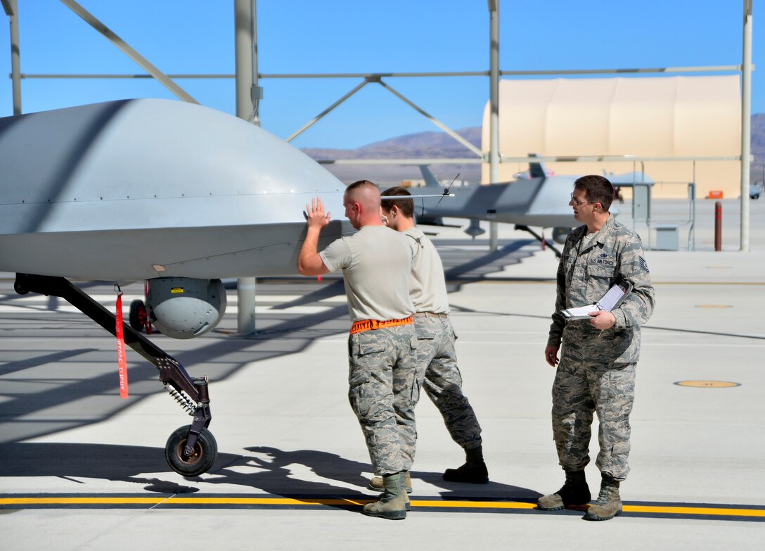 Tech. Sgt. Remington, 432nd Maintenance Group quality assurance inspector, watches as a 432nd Aircraft Maintenance Squadron Tiger Aircraft Maintenance Unit team checks the weight and balance of an MQ-1 Predator May 3, 2016. QA plays an essential role in completing the maintenance mission by ensuring maintainers follow technical orders and complete maintenance right. Missing minor mistakes or making maintenance errors can result in serious damage to aircraft and personnel. (U.S. Air Force photo by Senior Airman Christian Clausen/Released)