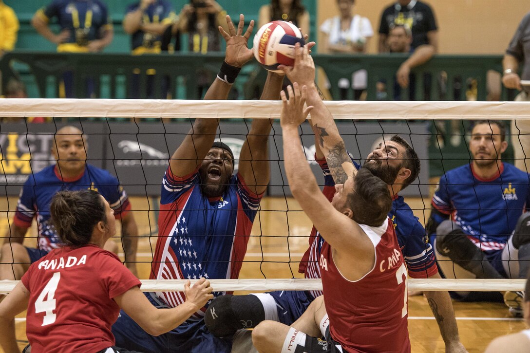 Army veteran Alexander Shaw, left center, and Air Force veteran Nicholas Dadgostar, right center, attempt to block the ball against the Canadian team during a sitting volleyball competition at the 2016 Invictus Games in Orlando, Fla., May 7, 2016. Also pictured are Special Operations Command Sgt. 1st Class Alfred Martinez, left, and Army veteran Robbie Gaup, right. DoD photo by Roger Wollenberg