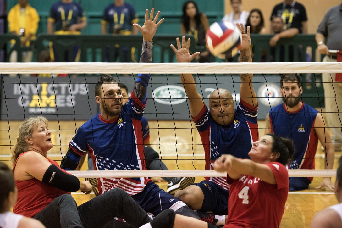 Army veteran Robbie Gaup, Special Operations Command Sgt. 1st Class Alfred Martinez and Army veteran Stefan LeRoy attempt to block the ball against the Canadian team during a sitting volleyball match at the 2016 Invictus Games in Orlando, Fla., May 7, 2016. DoD photo by Roger Wollenberg
