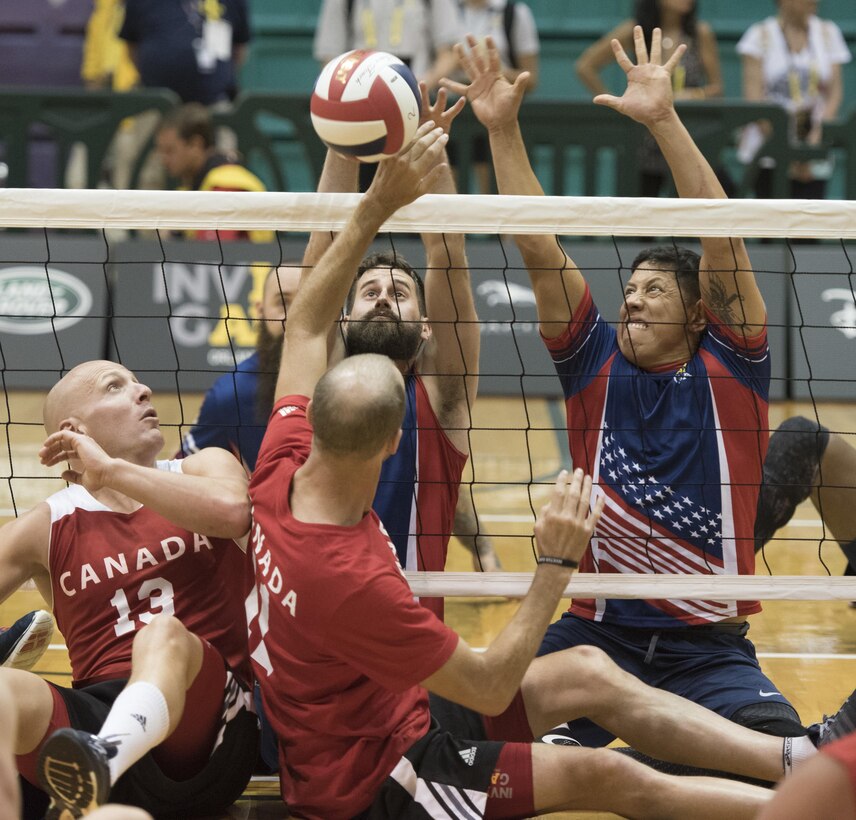 Army veteran Stefan LeRoy, left, and Marine Corps veteran Anthony Rios attempt to block the ball against the Canadian team during a sitting volleyball match at the 2016 Invictus Games in Orlando, Fla., May 7, 2016. DoD photo by Roger Wollenberg
