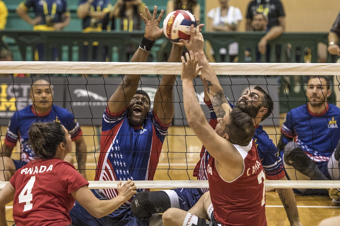 Army veteran Alexander Shaw, left center, and Air Force veteran Nicholas Dadgostar, right center, attempt to block the ball against the Canadian team playing a sitting volleyball competition during 2016 Invictus Games in Orlando, Fla., May 7, 2016. Also pictured are U.S. Special Operations Command Sgt. 1st Class Alfred Martinez left, and U.S. Army veteran Robbie Gaup, right. DoD photo by Roger Wollenberg