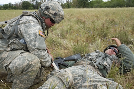 U.S. Army Pvt. Dante McCray (left), 238th Transportation Company (TC), applies a tourniquet to Spc. Franklin Gardner (right), 238th TC on Fort Hunter Liggett, Calif. on May 7, 2016. McCray and Gardner took part in training for their unit to set up a Tactical Assembly Area and got hit by enemy fire. McCray turned a belt into a makeshift tourniquet when Gardner became a casualty. (U.S. Army photo by Spc. Sean McCallon, 91st Training Division public affairs.)