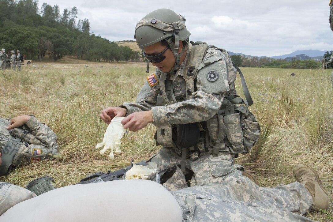 U.S. Army Sgt. Jinlin Zhang, 238th Transportation Company from Concord, Calif. puts on sterile gloves to render medical treatment to a casualty during a training exercise as part of the WAREX events hosted by the 91st Training Division. Zhang practices combat life saver procedures to provide aid to a casualty when his unit was experiencing enemy fire. (U.S. Army photo by Spc. Sean McCallon, 91st Training Division public affairs.)