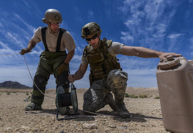 Staff Sgt. Jeffery Glover, 99th Civil Engineer Squadron explosive ordinance technician, and Senior Airman Kyle Osgood, 99th CES EOD technician, use a water jug as a counterweight to secure a line during a training exercise at Nellis Air Force Base, Nev., May 5, 2016. EOD technicians are assigned to some of the most dangerous missions, they perform tactically harrowing and technically demanding tasks in diverse environments worldwide. (U.S. Air Force photo by Airman 1st Class Kevin Tanenbaum)