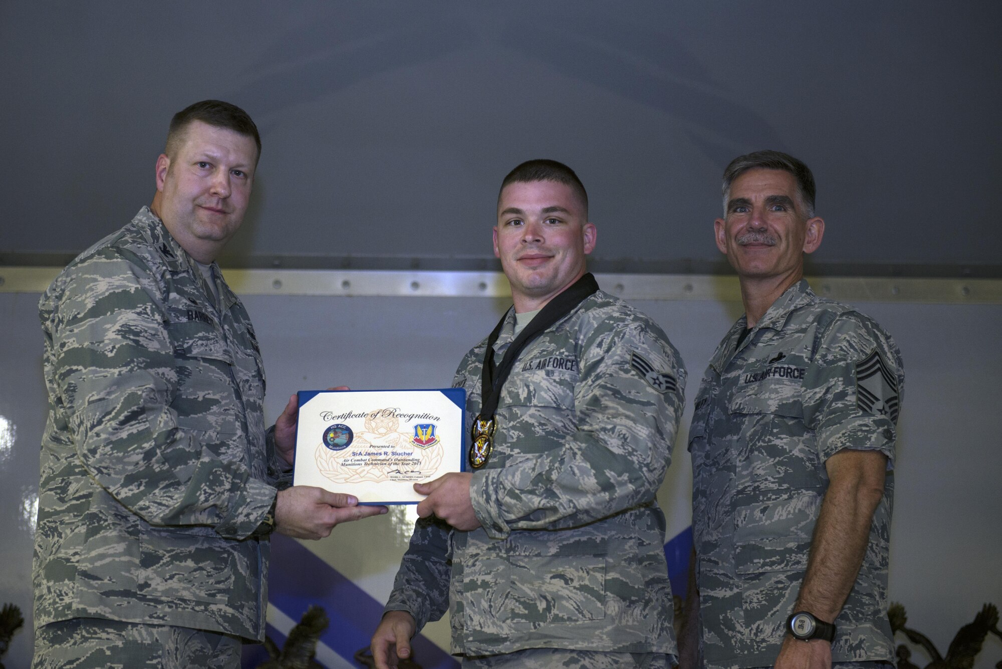 U.S. Air Force Col. Shane Barrett, 23d Maintenance Group commander, left, and Chief Master Sgt. Brinkley, 23d Maintenance Group chief enlisted manager, right, presents Senior Airman James Slucher, 23d Equipment Maintenance Squadron munitions technician, with the Munitions Technician of the Year award during the 2016 Maintenance Professional of the Year awards banquet, May 6, 2016, at Moody Air Force Base, Ga. Slucher is responsible for handling, storing and transporting weapons and locally disposing nonhazardous and unserviceable munitions. (U.S. Air Force photo by Airman 1st Class Greg Nash/Released) 