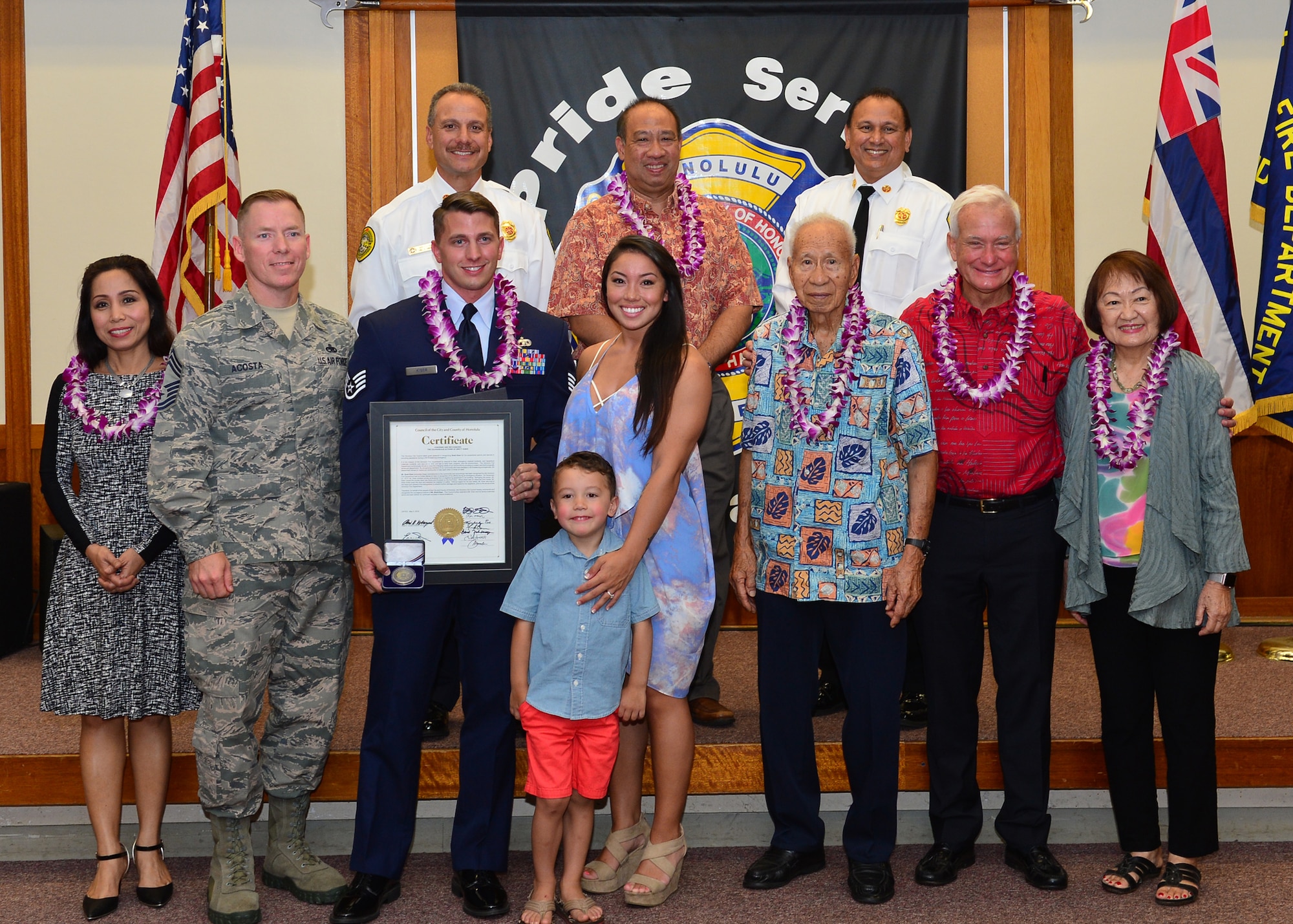 Staff Sgt. Brentt Kiser, 735th Air Mobility Squadron poses with his family, 735th AMS leadership, the mayor of Honolulu, as well Honolulu city council members, and Honolulu Fire Department leaders, after receiving The Honolulu Fire Departments Medal of Valor from Lionel Camara Jr., Honolulu Deputy Fire Chief, at the Mokulele Fire Station No. 8 May 5, 2016. The Medal of Valor is given to individuals that have acted with extreme heroism without regarded to personal safety. Kiser earned the medal after he purposely entered a smoke filled apartment to remove an incapacitated resident from a fire and pull him to safety. Kiser then went back into the apartment to put the fire out, preventing further damage to approximately 12 other apartments. (U.S. Air Force photo by Tech. Sgt. Aaron Oelrich/Realesed)       