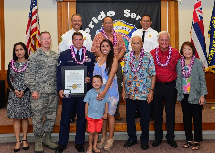 Staff Sgt. Brentt Kiser, 735th Air Mobility Squadron poses with his family, 735th AMS leadership, the mayor of Honolulu, as well Honolulu city council members, and Honolulu Fire Department leaders, after receiving The Honolulu Fire Departments Medal of Valor from Lionel Camara Jr., Honolulu Deputy Fire Chief, at the Mokulele Fire Station No. 8 May 5, 2016. The Medal of Valor is given to individuals that have acted with extreme heroism without regarded to personal safety. Kiser earned the medal after he purposely entered a smoke filled apartment to remove an incapacitated resident from a fire and pull him to safety. Kiser then went back into the apartment to put the fire out, preventing further damage to approximately 12 other apartments. (U.S. Air Force photo by Tech. Sgt. Aaron Oelrich/Realesed)       
