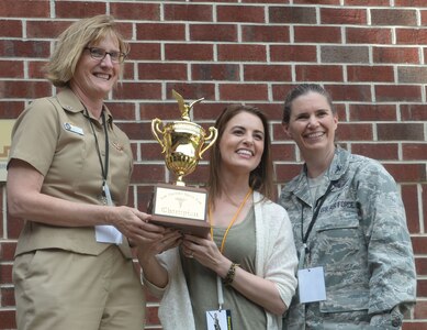 U.S. Navy Capt. Elizabeth Maley, Naval Health Clinic Charleston commander, hands the winning trophy to U.S. Air Force Civilian Brandy Wendler, 628th Medical Group flight chief and U.S. Air Force Col. Margret Jones, 628th Medical Group commander, at the end of the 2016 Lowcountry Skills Fair May 4, 2016, at Joint Base Charleston - Weapons Station, S.C. The fair was created to showcase and improve the skillset of medical professionals throughout the local area. (U.S. Air Force photo/Senior Airman Ericka Engblom)