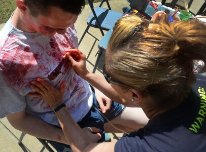U.S. Air Force Senior Airman Peter Boyd, 628th Medical Support Squadron biomedical equipment technician, gets covered in fake blood by U.S. Air Force Master Sgt. Caroline Bunce, 628th Aerospace Medical Squadron dental hygienist, during the 2016 Lowcountry Skills Fair May 4, 2016 at Joint Base Charleston - Weapons Station, S.C. The fair was created to showcase and improve the skillset of medical professionals throughout the local area. (U.S. Air Force photo/Senior Airman Ericka Engblom)