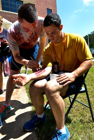 U.S. Air Force Senior Airman Paul Boyd, 628th Medical Support Squadron, biomedical equipment technician, applies moulage to Navy victim role player during the 2016 LowCountry Skills Fair, May 4, 2016, at Joint Base Charleston - Naval Weapons Station, S.C. The moulage assisted fair coordinators by providing a real injury aspect for competitors to practice on. (U.S. Air Force photo by Staff Sgt. Michael Battles)