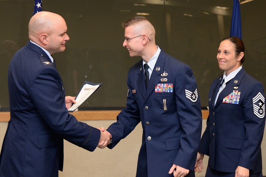 Staff Sgt. Matthew Stranz, 66th Air Base Group chaplain assistant, is congratulated by Col. David R. Dunklee, installation commander, during the Community College of the Air Force commencement at the Hanscom Conference Center May 6, as Hanscom Command Chief Master Sgt. Patricia A. Hickey looks on. More than 20 Airmen from Hanscom and geographically separated units received Associate in Applied Science degrees during the event. (U.S. Air Force photo by Linda LaBonte Britt)