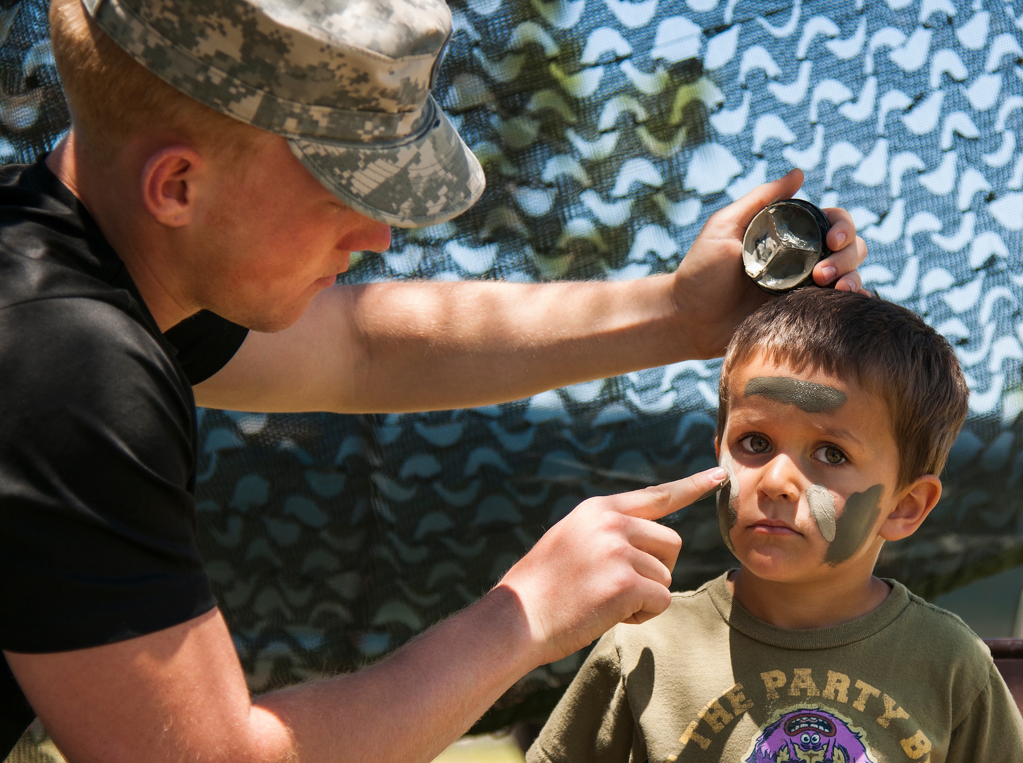 A Soldier applies war paint to a “future Ranger “during the 6th Ranger Training Battalion’s open house event May 7 at Eglin Air Force Base, Fla.  The event was a chance for the public to learn how Rangers train and operate. The event displays showed equipment, weapons, a reptile zoo, face painting and weapon firing among others. The demonstrations showed off hand-to-hand combat, a parachute jump, snake show, and Rangers in action. (U.S. Air Force photo/Samuel King Jr.)
