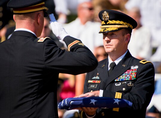 Brig. Gen. Kurt Ryan, commandant of the Army Ordnance School, accepts a folded flag to present to a family during the 47th Annual EOD Memorial Service at the Kauffman EOD Training Complex at Eglin Air Force Base, Fla., May 7. Names of recent fallen and past EOD technicians are added to the memorial wall during the ceremony each year.  The Army, Marines and Navy added six new names this year. The all-service total now stands at 320. (U.S. Air Force photo/Samuel King Jr.)