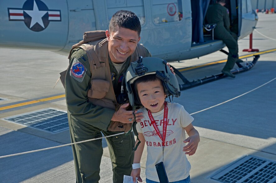 1st Lt. Vicente Vasquez, 459th Airlift Squadron scheduling officer, poses for a picture with a child during the 2016 Friendship Day, Air Show at Marine Corps Air Station Iwakuni, Japan, May 5, 2016. This year was the 40th Annual Friendship Day, offering a culturally enriching experience that displays the mutual support shared between the U.S. and Japan. (U.S. Air Force photo by Senior Airman David Owsianka/Released)