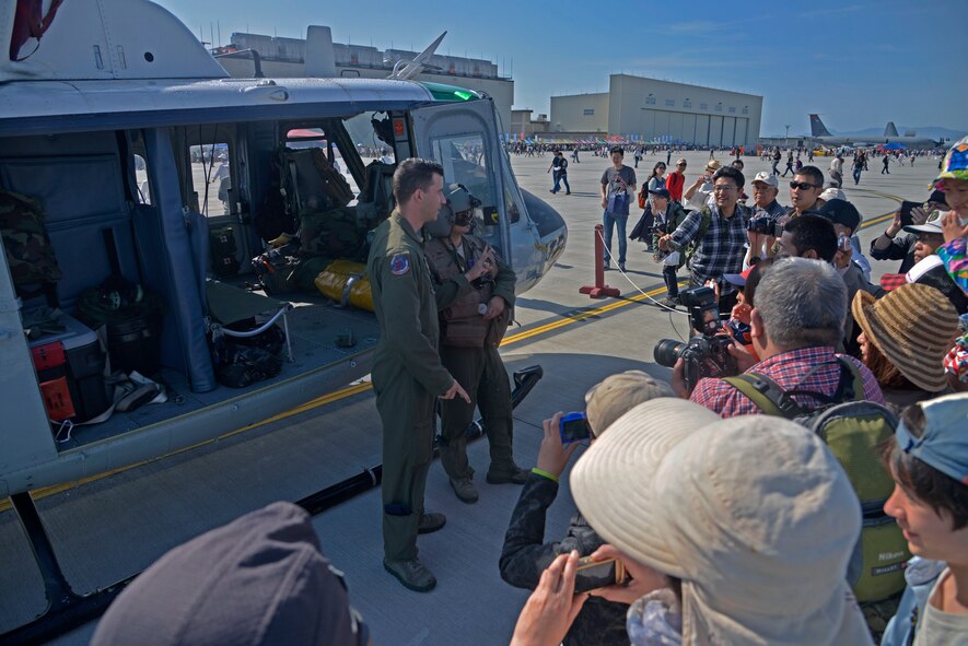 Staff Sgt. Nicholas Poe, 459th Airlift Squadron special mission aviator and 1st Lt. Vicente Vasquez, 459 AS scheduling officer, interact with people during the 2016 Friendship Day, Air Show at Marine Corps Air Station Iwakuni, Japan, May 5, 2016. Yokota Air Base showcased a UH-1N Huey and a C-12 Huron at the event. (U.S. Air Force photo by Senior Airman David Owsianka/Released)