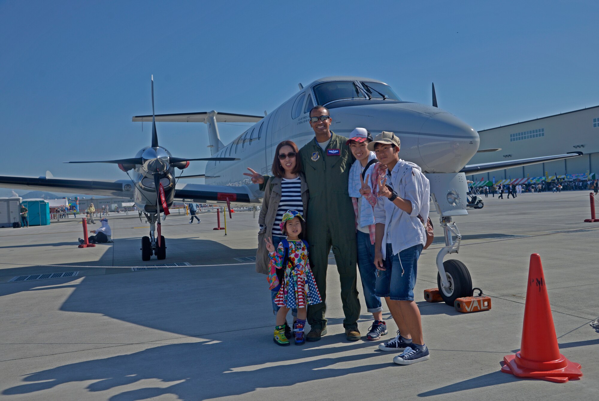Capt. Gershwyn Caruth, 459th Airlift Squadron assistant director of operations, poses for a picture with people at the 2016 Friendship Day, Air Show at Marine Corps Air Station Iwakuni, Japan, May 5, 2016. Yokota Air Base showcased a UH-1N Huey and a C-12 Huron at the event. (U.S. Air Force photo by Senior Airman David Owsianka/Released)