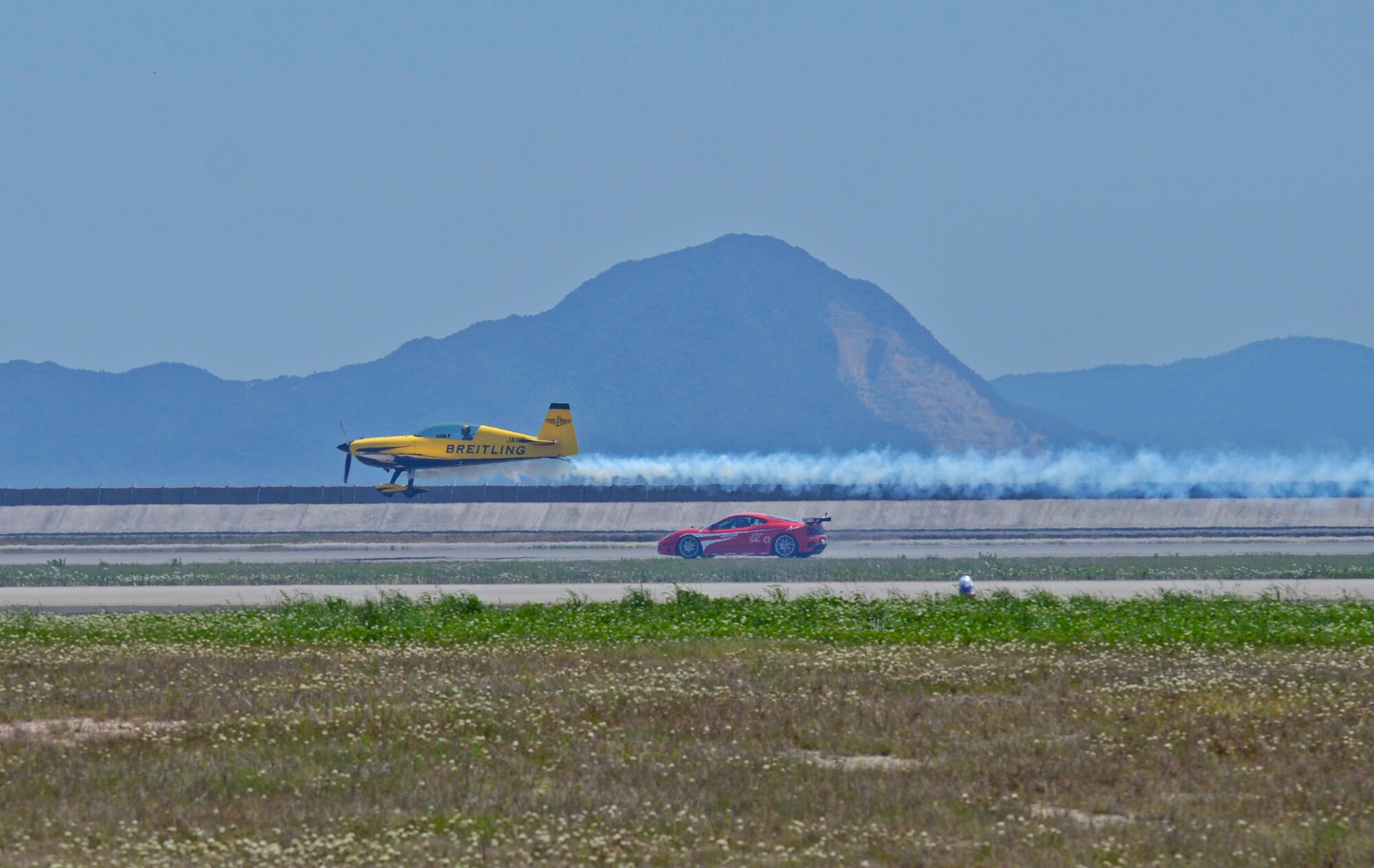 A Lufthansa Airbus A-320 flies past a Ferrari during the 2016 Friendship Day at Marine Corps Air Station Iwakuni, Japan, May 5, 2016. The event showcased a variety of static displays, aviation performances and demonstrations, and provided food and entertainment for guests of the largest single-day event at Iwakuni each year. (U.S. Air Force photo by Senior Airman David Owsianka/Released)