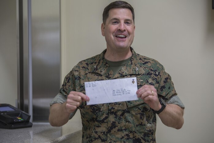 Col. Robert V. Boucher, commanding officer of Marine Corps Air Station Iwakuni, purchases the first postage stamp during the grand opening ceremony for the new south side post office on MCAS Iwakuni, Japan, May 9, 2016. The new post office will start delivering and sending mail on opening day. (U.S. Marine Corps photo by Cpl. Nathan Wicks/Released) 