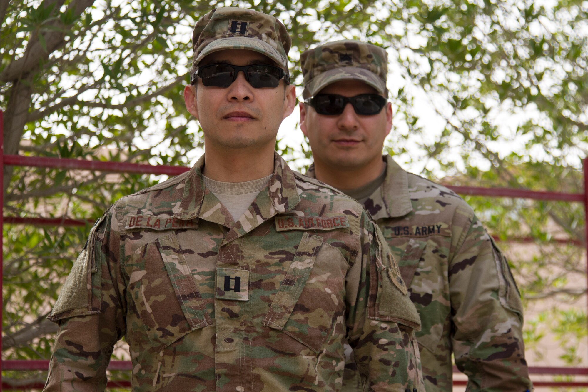 Sgt. Nicholas De La Pena, AFCENT Public Affairs Broadcast NCO, stand behind his big brother, Cpt. Nicholas De La Pena, AFCENT Lessons Learned Deputy Director, as they pose for a photo March 18 at Al Udeid Air Base, Qatar. The brothers have deployed together for the second time now. (U.S. Army photo by Spc. Travis Terreo)