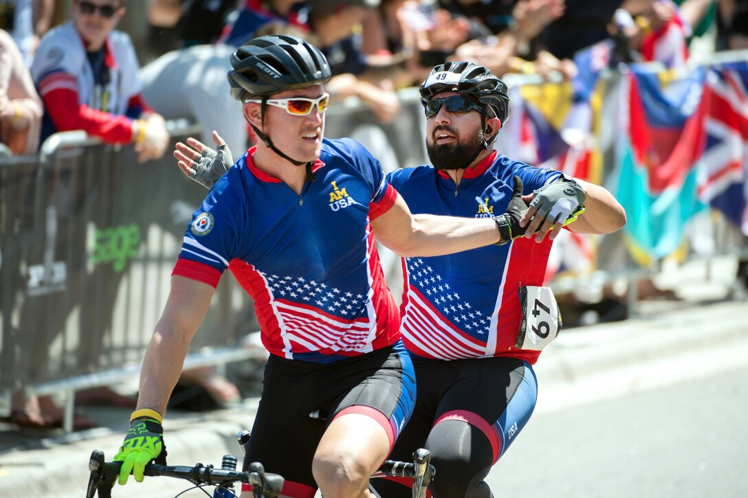 AJ Mohammed, back, a U.S. team member and visually impaired cyclist, celebrates finishing a race with his guide, Chris Suter, during the 2016 Invictus Games in Orlando, Fla., May 9, 2016. DoD photo by EJ Hersom