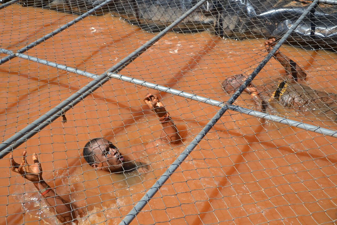 (Left to right) Army Reserve Recruiters Sgt. 1st Class Jomo Blair and Sgt. 1st Class Bob Chavis pull themselves, hand over hand, through the muddy "Cage Crawl" at the 2016 Atlanta Tough Mudder. Partnered with the Army Marketing Research Group, the muddy event was held May 7 and 8, 2016, at Bouckaert Farms in Fairburn, Ga.