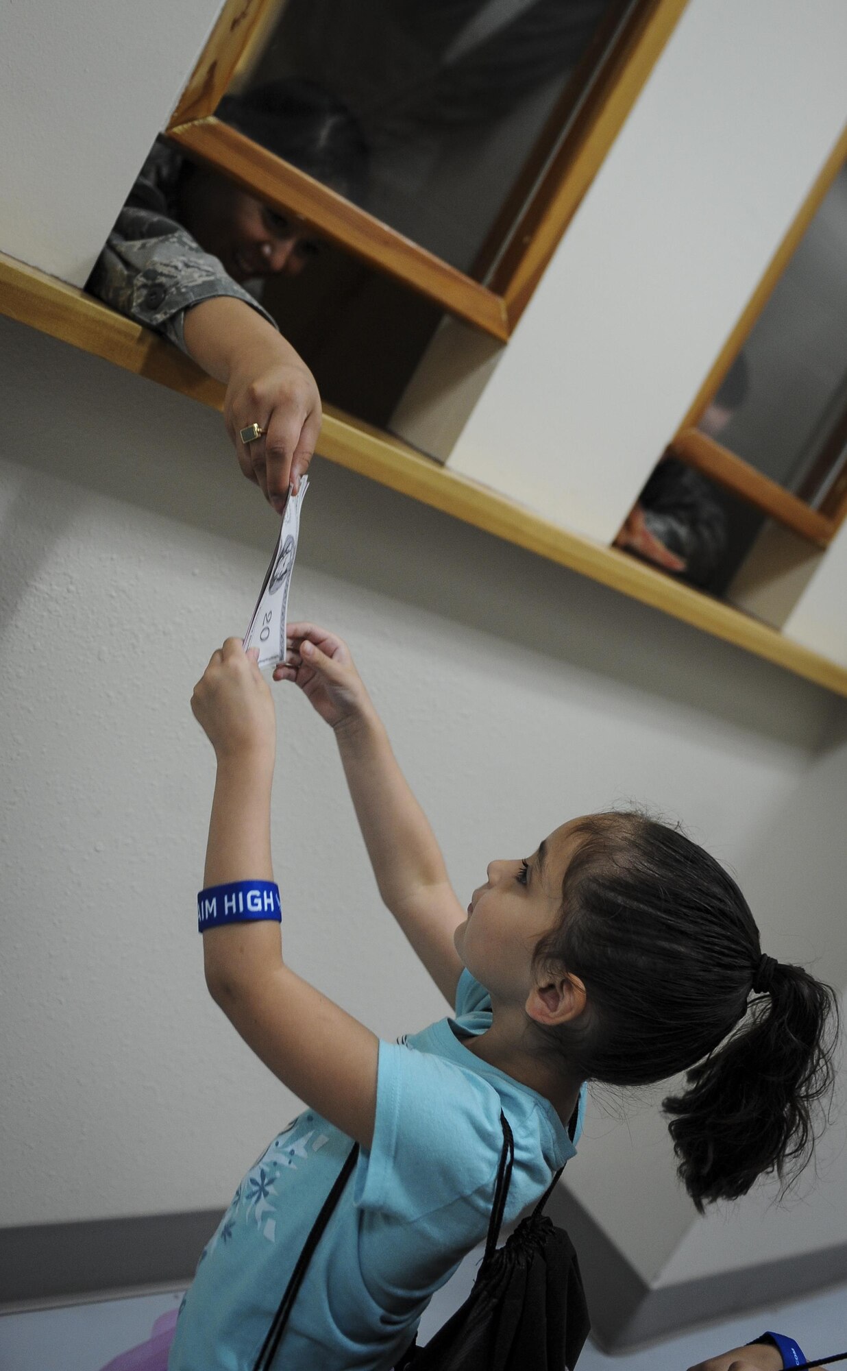 Airman 1st Class Alondra Gonzales Arroyo, a financial services technician with the 1st Special Operations Comptroller Squadron, hands a military child imitation money as part of a deployment line during Operation Kids Understanding Deployment Operations at Hurlburt Field, Fla., April 30, 2016. Operation KUDOS is an educational event aimed to help build resiliency in military youth by engaging them in activities that simulate the pre-deployment experience, such as pre-deployment lines and demonstrations and games held by multiple squadrons around Hurlburt. The event concluded with a “homecoming” where parents welcomed back their children. (U.S. Air Force photo by Senior Airman Meagan Schutter)
