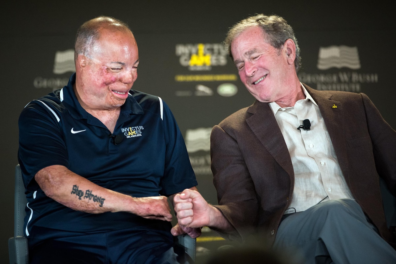 Former President George W. Bush fist bumps with Air Force Master Sgt. Israel Del Toro during the 2016 Invictus Games Symposium on Invisible Wounds in Orlando, Fla., May 8, 2016. The symposium, hosted by Bush and Britain’s Prince Harry, sought to destigmatize the victims of post-traumatic stress and other injuries that are not readily visible. DoD photo by EJ Hersom