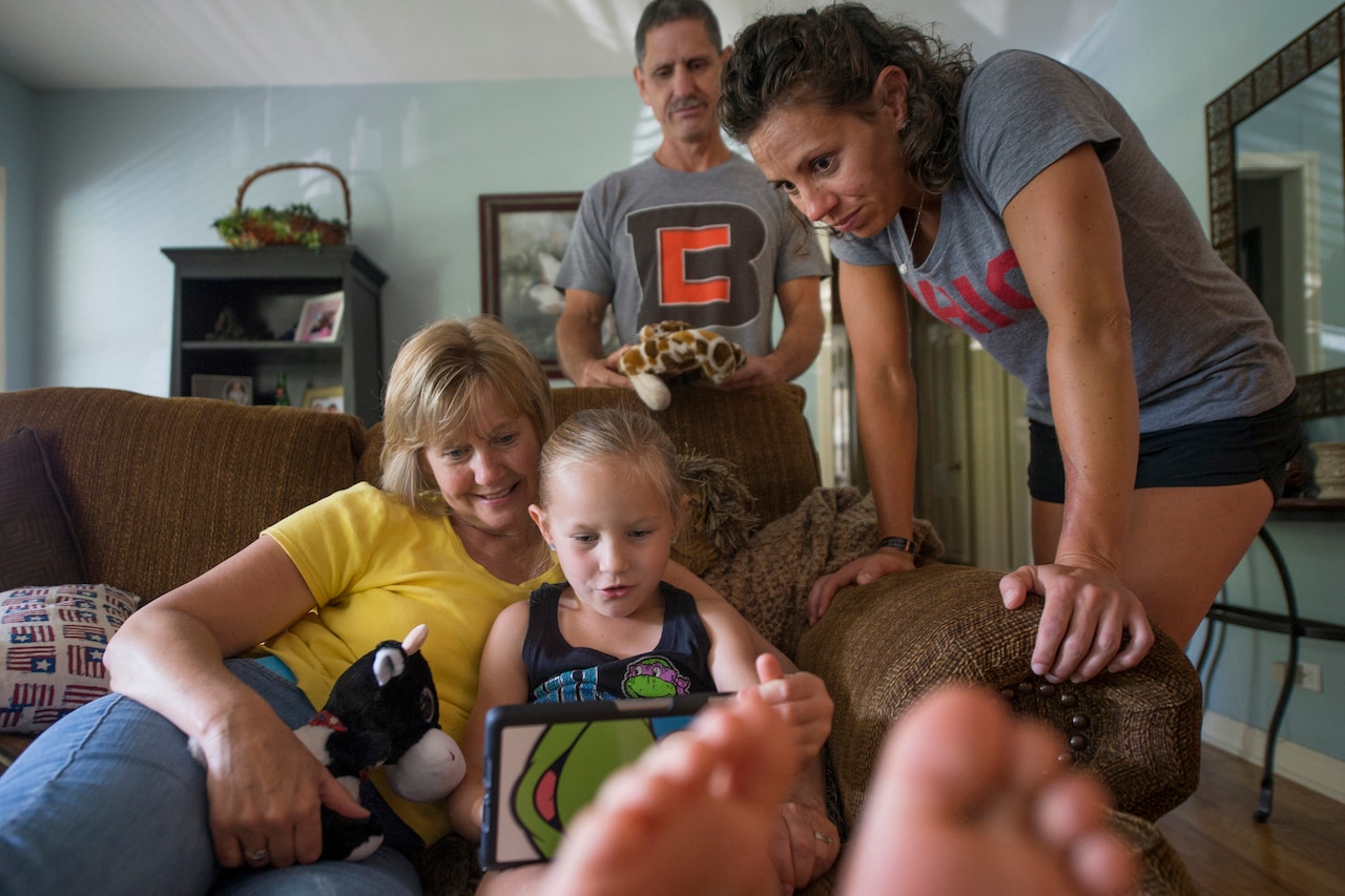 Jayden Elmlinger, then 6, practices reading while her grandmother Berti Elmlinger, grandfather, Mark Elmlinger, and mother, Army Capt. Kelly Elmlinger, look on in Kelly’s home in San Antonio, June 10, 2015. DoD photo by EJ Hersom