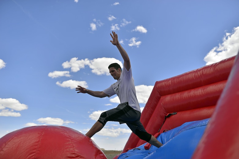 Master Sgt. Ben Leon, 379th Space Range Squadron, leaps across an inflatable obstacle during the annual Sexual Assault Awareness and Prevention Month inflatable run at the Schriever Air Force Base, Colorado, running path Thursday, May 5, 2016. Participants tackled “Wipe Out” TV show-style obstacle courses while running 2.5 miles on the running path behind the base fitness center. (U.S. Air Force Photo/Katie Calvert)