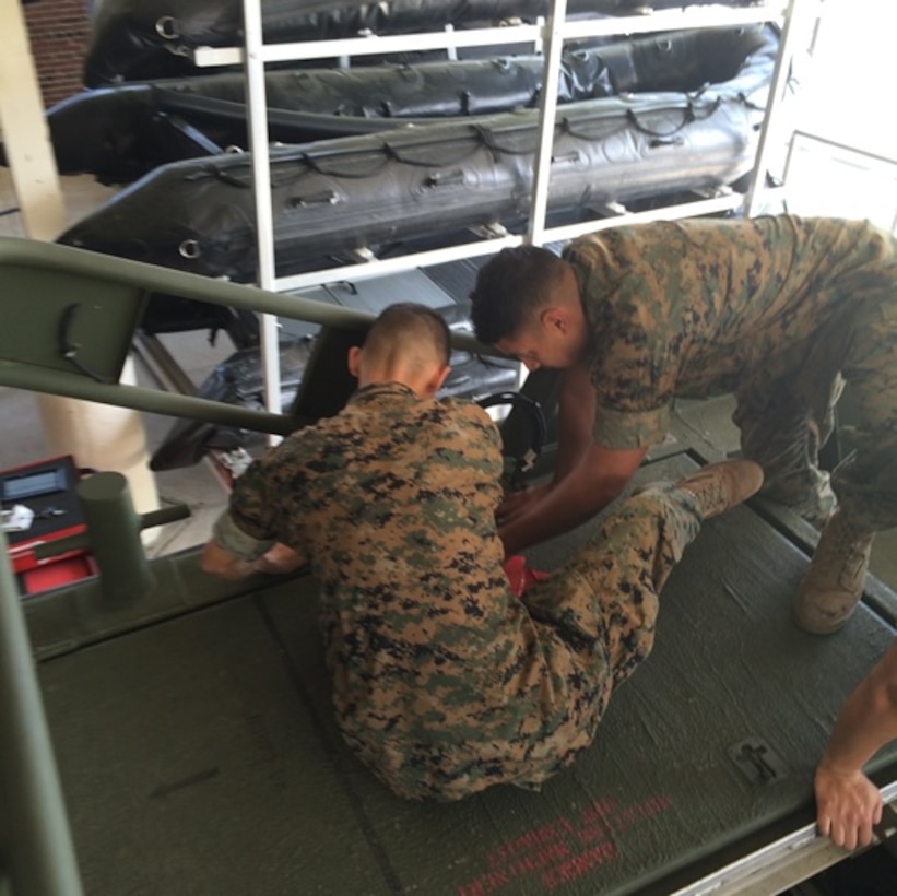 Lance Corporals Alan Bounyasith and Pablo Flores, Marines attached to Small Craft Mechanics course 3-16 (SCMC 3-16); perform Preventative Maintenance Checks and Services (PMCS) on the Bridge Erection Boat (BEB) as part of a practical application. These students are removing the engine hatches in order to clean and lubricate the hinges.

