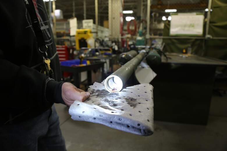 Michael Brown, arillery repair leader, demonstrates the excessive seepage of hydraulic fluid from a M777 howitzer scavenge manifold and cylinder being tested by the BOLTS test bench designed by Jacob Zeman, artillery repairer, at Production Plant Barstow aboard Marine Corps Logistics Base Barstow's Yermo annex, Calif. The BOLTS system is one of a kind and cannot even be found at the manufacturer's facilities. 