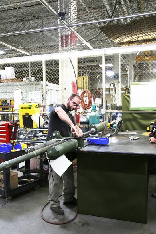 Jacob Zeman, artillery repairer makes adjustments to the BOLTS test bench he designed and built at Production Plant Barstow, aboard Marine Corps Logistics Base Barstow, Calif. By design the M777 scavenge manifold and cylinder was engineered to allow a small amount of weeping, but this test bench allows for testing and repair to ensure optimal functioning. 