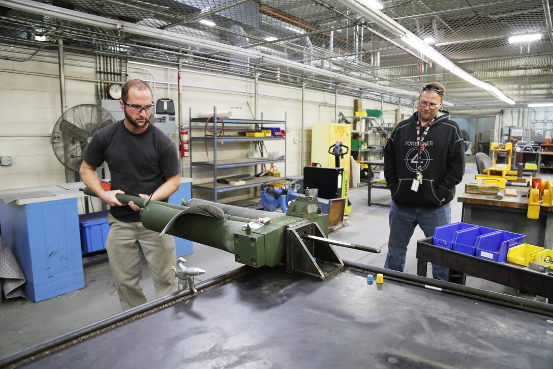 Jacob Zeman, artillery repairer with Plant Barstow demonstrates the BOLTS test bench he designed and built to test components from the M777 Lightweight howitzer with support and guidance from Michael Brown, artillery repair leader, aboard Marine Corps Logistics Base Barstow's Yermo Annex. The BOLTS test bench is the only one of its kind and helps ensure that M777 howitzers going out to the war-fighters in the field are fully operational.  