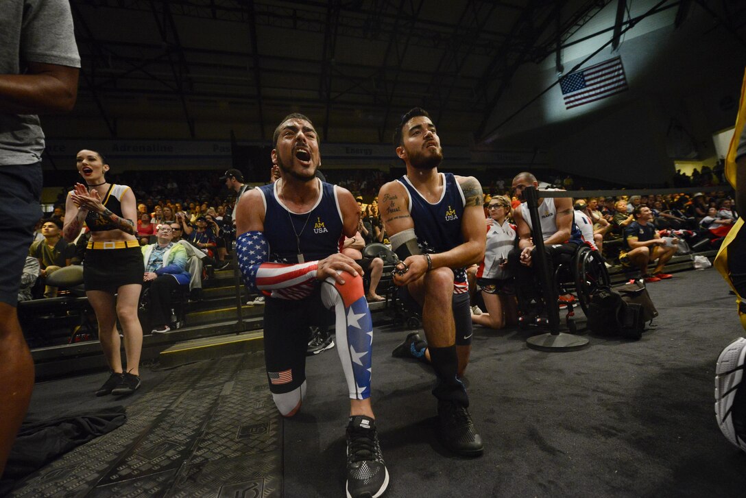 Retired Army Staff Sgt. Michael Kacer, left, and retired Air Force Staff Sgt. Daniel Crane cheer on a teammate competing in a rowing event during the 2016 Invictus Games in Orlando, Fla., May 9, 2016. Air Force photo by Tech. Sgt. Joshua L. DeMotts