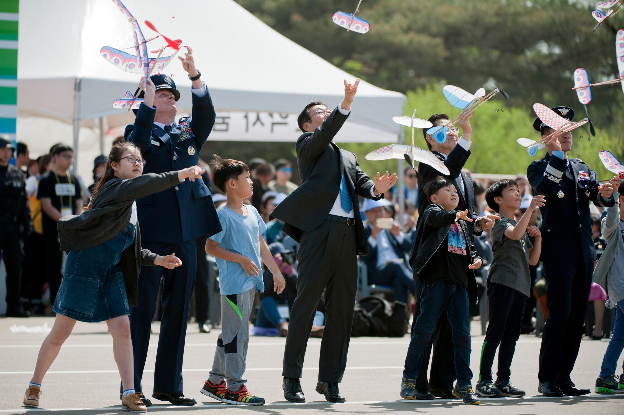 U.S. Air Force Brig. Gen. Kyle Robinson, 7th Air Force vice commander, and other distinguished visitors,  throw toy aircraft with children during the opening ceremony of the Gyeonggi Suwon Airshow 2016 at Suwon Air Base, Republic of Korea, May 7, 2016. The 51st Fighter Wing brought aircraft maintainers, pilots, an F-16 Fighting Falcon and an A-10 Thunderbolt II to the airshow to highlight the wing’s mission. (U.S. Air Force photo by Staff Sgt. Jonathan Steffen/Released)