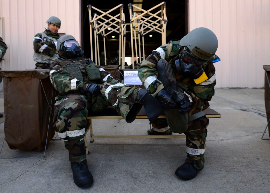 Airmen from the 51st Civil Engineer Squadron take off their Mission Oriented Protective Posture boots while going through a mock-decontamination line at Osan Air Base, Republic of Korea, May 11, 2016. The 51st CES held a training event during Exercise Beverly Herd 16-01 to give CES Airmen a chance to practice wartime survival skills. (U.S. Air Force photo by Senior Airman Victor J. Caputo/Released)